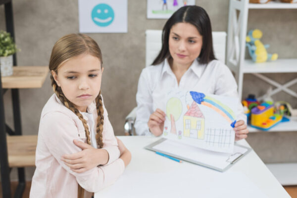 angry-blonde-little-girl-looking-drawing-paper-shown-by-her-psychologist